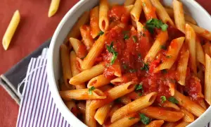 En skål med penne pasta arrabiata, toppad med färsk persilja. Enkel och smakrik italiensk klassiker.