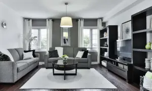 Nowoczesny szaro czarny salon z dwoma szarymi sofami, czarnym stolikiem kawowym i regałem.