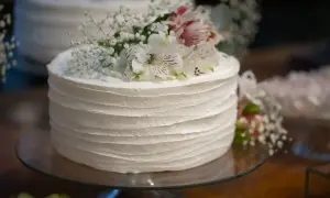 Biały tort udekorowany delikatnymi, żywymi kwiatami i gipsówką. Idealne, jakie żywe kwiaty na tort na specjalną okazję.