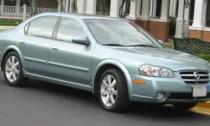 Jasnoniebieski Nissan Maxima 3.5 Turbo stoi przed domem z werandą.