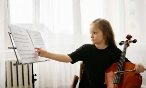 Dziewczynka z wiolonczelą przy nutach. Nauka gry na wiolonczeli to jej pasja.