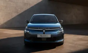 Elegancki, niebieski Lancia Ypsilon 2024 z nowoczesnym przodem, prezentowany na tle betonowej ściany.