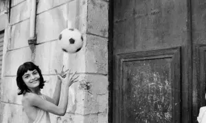 Letizia Battaglia giovane gioca con un pallone, un'immagine che cattura la spensieratezza dell'infanzia.