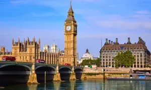 Big Ben Londyn z czerwonymi autobusami na moście i rzeką w tle.