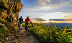 Dwóch rowerzystów przemierza malownicze trasy rowerowe w Polsce, podziwiając zachód słońca nad wzgórzami.