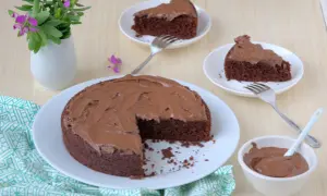 Una deliziosa torta al cioccolato senza glutine, con una fetta mancante e altre due servite su piattini, pronte per essere gustate.