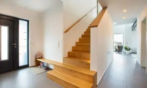 Moderne Ideen für den Hauseingang: Eine Holztreppe mit integrierter Sitzbank und Schuhablage lädt zum Eintreten ein.