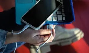 Dłoń podłącza kabel USB do laptopa, aby naładować twój telefon.