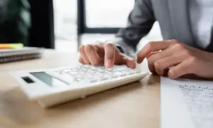 Dłonie wpisują liczby na białym kalkulatorze. Wiron 1m stopa składana pomaga w precyzyjnych obliczeniach.