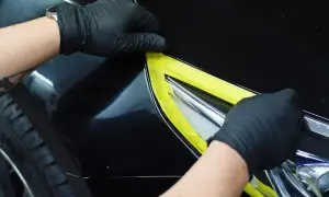 Ręczne przygotowanie do polerowania auta: zakładanie taśmy maskującej na reflektor. Perfekcyjne wykończenie to klucz do tego, jak wypolerować auto ręcznie.