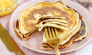 Ein goldener Löffel hebt einen Stapel fluffiger Pfannkuchen an. Dieses Pfannkuchen Rezept von Oma ist ein Genuss!