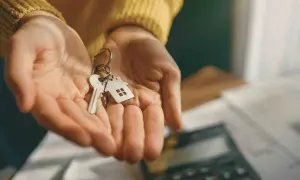 Mani che offrono chiavi con ciondolo a forma di casa, simbolo di donazione con usufrutto: vantaggi e svantaggi da valutare.