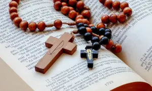 Drewnany różaniec i krzyż na otwartej Biblii. Symbolika modlitwy i wiary, która towarzyszy, kiedy zaczyna działać nowenna pompejańska.