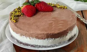 Deliziosa torta al gelato al cioccolato e panna, decorata con fragole, pistacchi e menta.