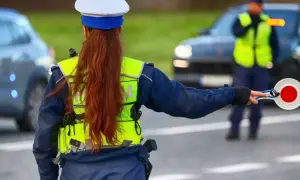 Policjantka zatrzymuje ruch, by uniknąć mandatu 24 punkty karne. Inny funkcjonariusz kieruje ruchem.
