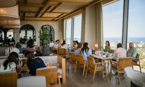 Goście delektują się posiłkiem w restauracji Olivia Star, przeglądając menu i podziwiając widok.