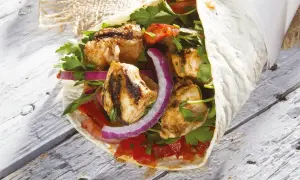 Kebab z grillowanym kurczakiem, warzywami i ziołami zawinięty w placek.