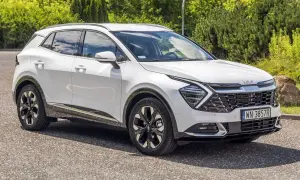 Biały Kia Sportage 1.6 benzyna zaparkowany na tle zieleni. Nowoczesny design i eleganckie felgi.