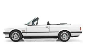 Vit cabriolet, en klassisk bmw 80 tal, med taket nere. Perfekt för sommarvägar.