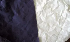 Dwa kawałki materiału, ciemnofioletowy i biały, leżą obok siebie. Czy bawełna to dobry materiał? Tak, jest miękka i oddychająca.