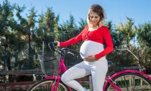 Kobieta w ciąży na rowerze, zastanawia się, czy w ciąży można jeździć na rowerze. Aktywność fizyczna jest ważna.