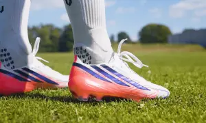 Scarpa calcio Adidas bianca con dettagli blu e rosa fluo. Pronta per scendere in campo e dominare la partita.