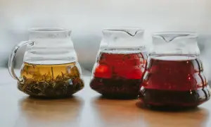 Trzy szklane dzbanki z zaparzoną herbatą: zieloną, czerwoną i ciemnoczerwoną. Pokazują, jak zaparzyć herbatę bez zaparzacza.