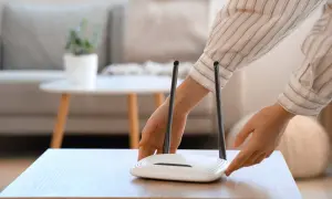 Ręce dotykają routera Wi-Fi. Chcesz wiedzieć, jak sprawdzić hasło do Wi-Fi?