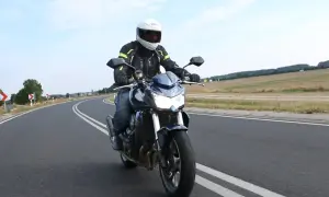 Motocyklista na Kawasaki Z750 2010 przemierza krętą drogę pośród pól.