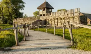 Drewniana kładka prowadzi do grodziska z wieżą obronną. To fragment szlaku piastowskiego, gdzie historia ożywa.