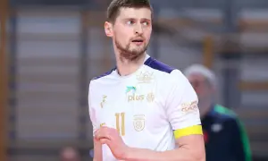 Piotr Nowakowski, siatkarz w białej koszulce z numerem 11, z uwagą obserwuje grę.