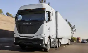 Le Nikola One, un camion blanc futuriste, roule sur l'autoroute sous un ciel bleu clair.