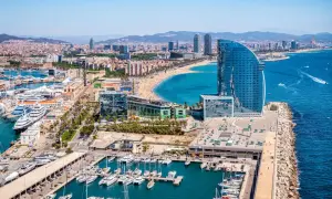 Widok na Barcelonę i jej piękne morze, z luksusowymi jachtami w porcie i nowoczesnym hotelem w kształcie żagla.