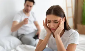 Mujer angustiada, con las manos en la cabeza, mientras su pareja le grita. Siente que mi mujer me maltrata psicológicamente.