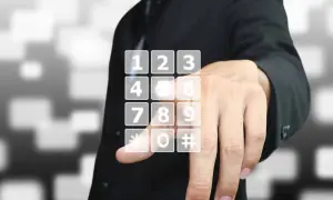 Dłoń wybiera wirtualny numer telefonu na ekranie.