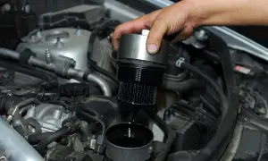 Cambio olio motore: un meccanico rimuove il filtro olio esausto, mostrando dove si trova nel vano motore.
