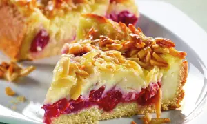 Ein Stück von Omas Kirschkuchen mit Pudding, belegt mit Mandelblättchen. Saftige Kirschen und cremiger Pudding unter knuspriger Kruste.