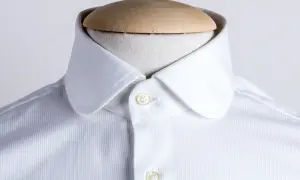 Dettaglio di una camicia bianca con colletto arrotondato, uno dei tanti tipi di colletto camicia, su un manichino.