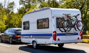 Schwarzer Kombi zieht Wohnwagen mit Fahrrädern, bereit für den Urlaub. B96 oder BE, das ist hier die Frage für die Reise.