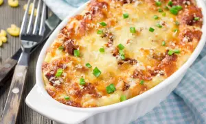Zapiekane mac and cheese z chrupiącym serem i zieloną cebulką, gotowe do podania.