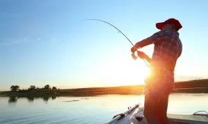 Chwila łowienia z łodzi, idealny spinning na szczupaka z brzegu. Słońce zachodzi nad spokojną wodą.