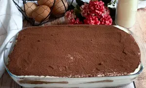 Tiramisù pronto per essere gustato! La ricetta tiramisù con 500 g mascarpone è un classico. Uova, fiori e latte completano la scena.