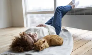 Mujer sonríe con su gato naranja sobre una manta, disfrutando del calor de la aerotermia en un piso.