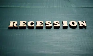Drewniane litery układają słowo "RECESSION". To pojęcie ekonomiczne, które opisuje spowolnienie gospodarcze.