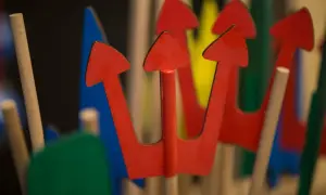 Czerwone, drewniane bierki z niebieskimi i zielonymi elementami w tle.