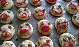 Lustige kleine Pizzen mit Olivenaugen und Paprikamund, perfekt zum glutenfrei essen.