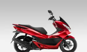 Czerwony skuter Honda PCX 125 na białym tle, widok z boku.
