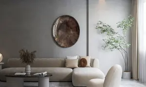 Salon w stylu japońskim skandynawskim. Jasna sofa, okrągły stolik, dekoracyjna taca na ścianie i drzewko bonsai tworzą harmonię.
