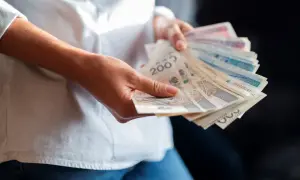 Ręce trzymające polskie banknoty. Zastanawiasz się, jaka będzie najniższa krajowa 2025 i ile na rękę dostaniesz?