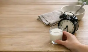 Un bicchiere di kefir pronto per essere gustato. L'orologio indica che è ora di bere kefir la sera.